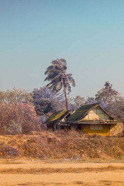 Infrared photography, a rustic, yellow house with a slanted roof nestled in a somewhat barren landscape clipart