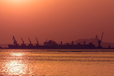 Kızıl ötesi fotoğrafçılık, canlı turuncu ve mor bir gün batımına karşı silueti olan uzak bir kargo gemisi.