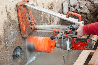 Nispeten hafif bir makine beton yapılarda büyük delikler açmak için çalışır..