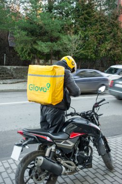Uzhgorod.Ukrayna Nisan 05.04.2023.Glovo kuryesi siparişin zamanında teslim edilmesi için bir motosiklet hazırlar.