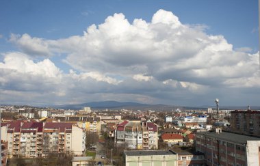 Uzhhorod şehrinin mimari manzarasına karşı dağlar, beyaz bulutlar ve mavi gökyüzü.