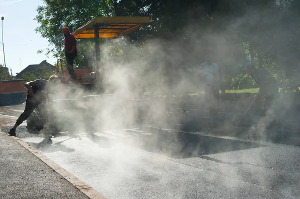Uzhgorod. Ukrayna. Ekim. 06.10.2022. Asfalt döşeme işi o kadar hızlı ilerliyor ki buhar yükseliyor.