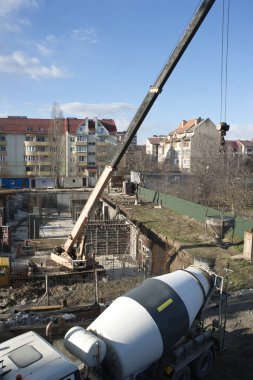 Kamyon mikseri, çok katlı binanın yük taşıyıcı yapılarını dökmek için inşaat alanına beton çözeltiyi teslim etti..