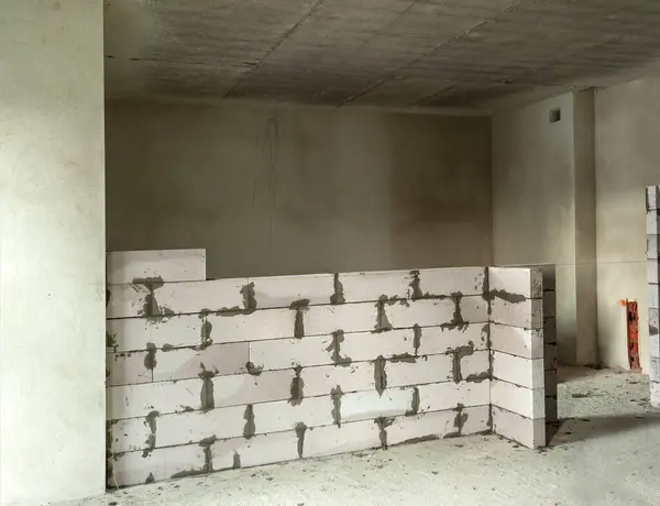 Oturma odasının duvarları arasında beyaz havalandırmalı beton bloklardan yapılmış bir bölme.