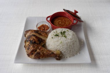 African dishe culinary Still Life. Chicken mafe with Grilled chicken, rice accompaniement and spicy sauce