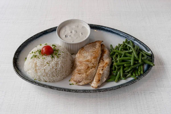 Middle East dishe culinary Still Life. Fried cutlet with tomatoes, green bean and rice accompaniement and White sauce