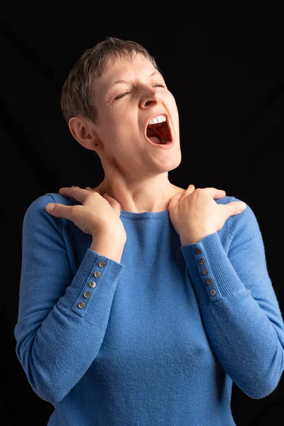 スタジオショットの女性Yawns彼女の肩の上に彼女の手で 短い髪を身に着けている青いセーターでカフスボタン — ストック写真