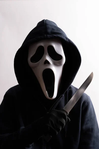 Stock image Packshot of Mask. An anonymous man with a white mask and a hood on the head holds a knife