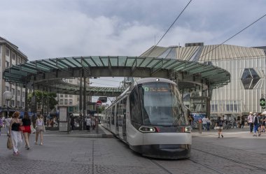 Strasbourg, Fransa - 06: 26 2023 Demir Adam Meydanı tramvay kavşağından bir tramvay ve kubbenin altında bekleyen insanlar