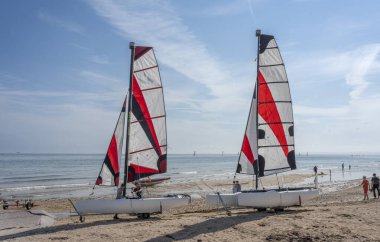 Langrune-Sur-Mer, Fransa - 07: 20 2023: Yelkenli tekneler kumsalda genç insanlarla birlikte duruyor