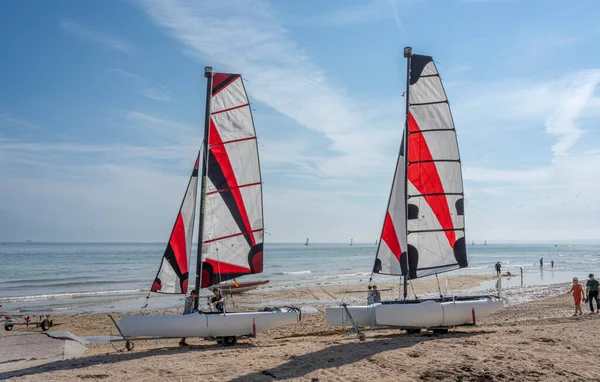 Langrune-Sur-Mer, Fransa - 07: 20 2023: Yelkenli tekneler kumsalda genç insanlarla birlikte duruyor