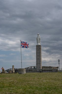 Arromanches-les-Bains, Fransa - 07: 21 2023: Bakire Meryem Anıtı 'nın görünüşü D Günü için bir İngiliz bayrağı ve Calvary üzerinde bulutlu gökyüzü