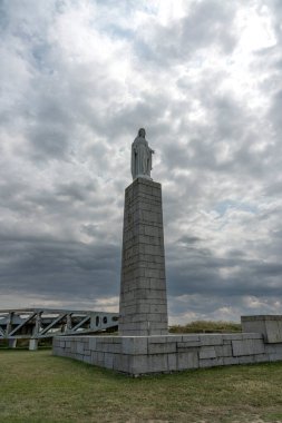 Arromanches-les-Bains, Fransa - 07: 07: 21 2023: Gaziler için anıt, Bakire Meryem Heykeli ve bulutlu ve güneşli bir gökyüzü altında metalik köprü