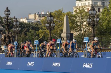 Paris, Fransa - 08 17 2023: Paris 2024 triatlon test etkinliği. Alexandre II köprüsündeki bisiklet yarışında kadın triatletler