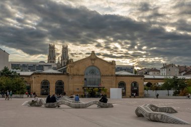 Nancy, Fransa - 09 01 2023: Nancy tren istasyonu binasının ön cephesi, metal bankların olduğu meydan ve arka planda Saint-Leon kilisesinin kuleleri