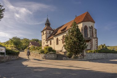 Dambach-La-Ville, Fransa - 09 05 2023: Alsatian Vineyard. Dambach-La-Ville köyü yakınlarındaki San Sebastian Şapeli 'nin manzarası ve bir binici ve atı.