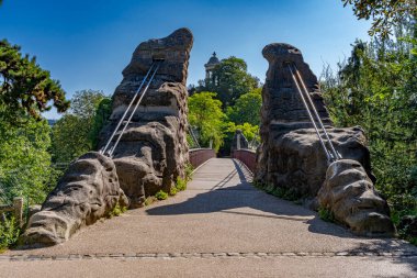 Park des Buttes Chaumont. Footbridge 'in Belvedere Adası' na, Sibyl Tapınağı 'na ve arkadaki binalara olan görüntüsü.