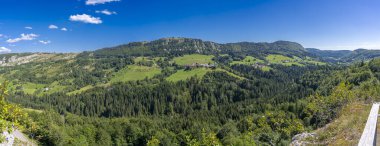 Les Bouchoux 'un köy, tepeler, ormanlar ve promontuar manzarası.