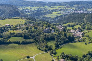 Les Bouchoux 'un köy, tepeler, ormanlar ve promontuar manzarası.