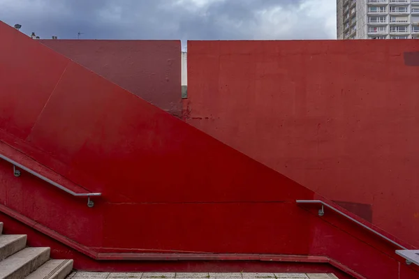 View of a graphic red wall and staircase with steps and ramp in the city