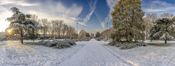 Gennevilliers, France - 12 18 2024: Eco-neighborhood. View of alignment of trees along a pathway under the snow