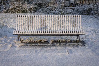 Gennevilliers, Fransa - 12 18 2024: Eco-Mahallesi. Parkta karla kaplı metal bir bankın görüntüsü