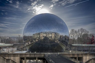 Paris, Fransa - 027 2024 Villette Kanalı. La Geode 'nin panoramik görüntüsü Bilim ve Endüstri Müzesi' nin yansıması, park ve güneş arkasında