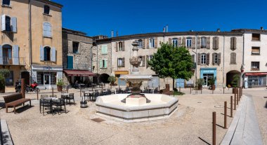 Sauve, Fransa - 04 16 2024: Tepedeki köyde fıskiyesi ve renkli binası olan tipik bir Occitan mekanının panoramik görünümü