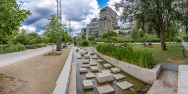 Paris, Fransa - 07: 20 2024: Clichy-Batignolles Martin Luther King Park. Parkın gölet manzarası bitki örtüsü ve çevresindeki binalar