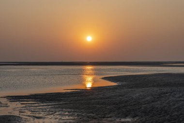 Denizin üzerinde gün batımı manzarası ve sahilden sarı bir şamandıra.