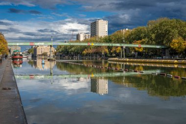 Paris, Fransa - 10 10 10 2024: Ourcq Kanalı. Stalingrad Savaş Meydanı 'ndan gelen konut binalarının, köprünün, mavnaların ve ağaçların yansımaları.