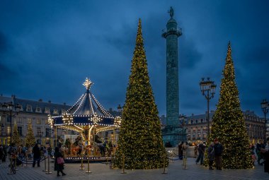 Paris, Fransa - 12.11.2024 Vendome Meydanı. Vendome sütunlu, noel ağaçlı, atlıkarıncalı ve gece dekorasyonlu bir yer.