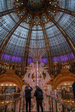 Paris, Fransa - 12: 2024: Kubbenin merkezini süsleyen Paris 'teki ünlü bir mağazanın içindeki devasa bir Noel ağacının görüntüsü.