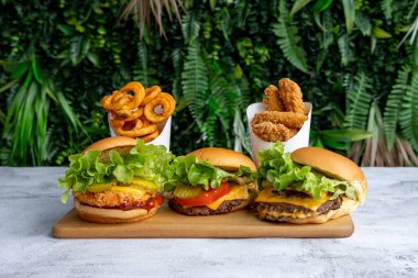 Üç peynirli burger, doğranmış biftek, ekilmiş tavuk göğsü, çedar peyniri, domates, salata, bir paket bonfile ve patates kızartması.