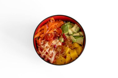 Hawaii mutfağı natürmort. Yukarıdan bakıldığında domatesli, havuçlu, mangolu, nar ve avokadolu Baharatlı Somon Poke Kasesi.