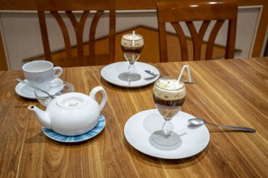 İki bardak İrlanda kahvesi, iki tabak, ahşap bir masa, bir çaydanlık ve bir fincan