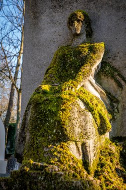 Paris, Fransa - 02 02 02 2025: Pere-Lachaise Mezarlığı. Mezarın üstünde yeşil yosun kaplı eski bir kadın heykeli.