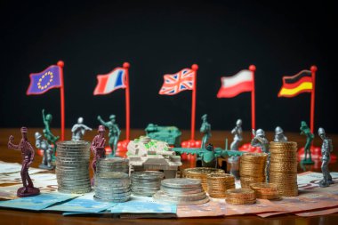 Arkaplanda altın ve avro desteleri, asker, savaş uçağı, tank ve Avrupa bayraklarının olduğu banknotlar