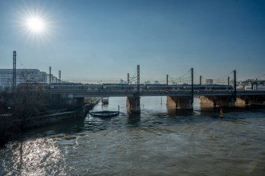 Gennevilliers, Fransa - 02 03 2025: Seine Nehri manzarası, metro treni ve Clichy Köprüsü 'nün arka planında La Defense kuleleri olan bir demiryolu köprüsü