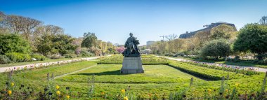 Paris, Fransa - 04 05 2025: Jardin des Plantes. Botanik bahçesinin panoramik manzarası Jean Carlus 'un heykeli ve arkasında iki büyük Japon kiraz ağacı.