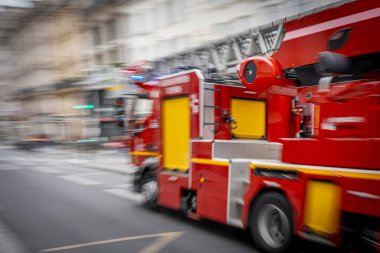 Paris, Fransa - 04 19 2025: Merdivenli kırmızı bir itfaiye aracı acil müdahale için Paris caddesinde son sürat ilerliyor