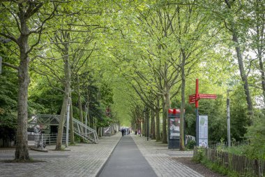 Paris, Fransa - 04 26 2025: Parc de la Villette. Yürüyen insanlarla dolu kaldırımlı bir yaya caddesi manzarası