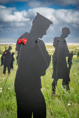 Vers-Sur-Mer, Fransa - 05 16 2025: British Normandy Memorial. The Standing with Giants 'ın panoramik görüntüsü. Kırmızı gelincikli bir asker silueti.