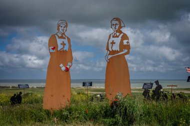 Vers-Sur-Mer, Fransa - 05 16 2025: British Normandy Memorial. The Standing with Giants 'ın panoramik görüntüsü. İki hemşire silueti var.