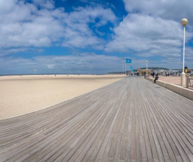 Deauville, Fransa - 05: 17 2025 Deauville Plajı. Sahilin panoramik manzarası Deauville tahtaları, kum, deniz ve bulutlu mavi gökyüzü