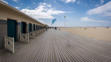 Deauville, Fransa - 05: 17 2025 Deauville Plajı. Sahilin panoramik manzarası Deauville tahtaları, kum, deniz ve bulutlu mavi gökyüzü