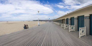 Deauville, Fransa - 05: 17 2025 Deauville Plajı. Sahilin panoramik manzarası Deauville tahtaları, kum, deniz ve bulutlu mavi gökyüzü