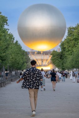 Paris, Fransa - 07 03 2025: Önünde Olimpiyat kazanı olan genç bir adam Tuileries bahçesinde yürüyor
