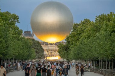 Paris, Fransa - 07 03 2025: Bir ara sokakta yürüyen turistlerin panoramik manzarası, Tuileries bahçesindeki büyük yuvarlak havzaya yerleştirilmiş Olimpiyat kazanına bakıyor