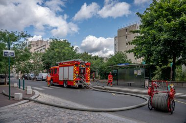 Gennevilliers, Fransa - 07: 14: 2025: Bir grup itfaiyeci ve kırmızı itfaiye aracı bir binada yangını söndürmek için harekete geçti